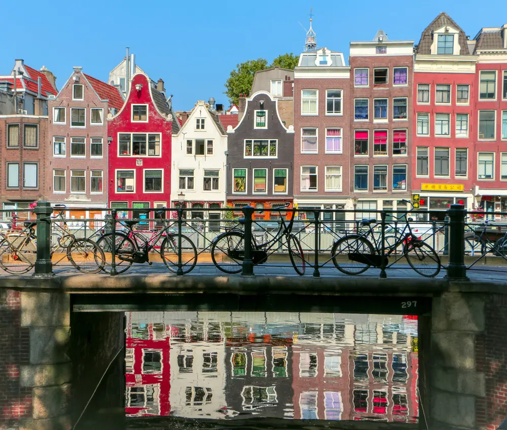 Gabled canal houses reflected in a quiet Amsterdam canal, illustrating safe and elegant Amsterdam solo travel for women over 50.
