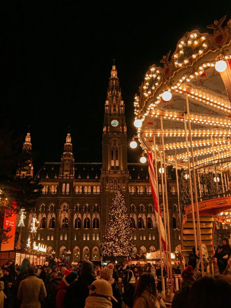 A glowing European Christmas market with a lit tree and wooden stalls in the snow, illustrating the best Christmas markets in Europe for women over 50.