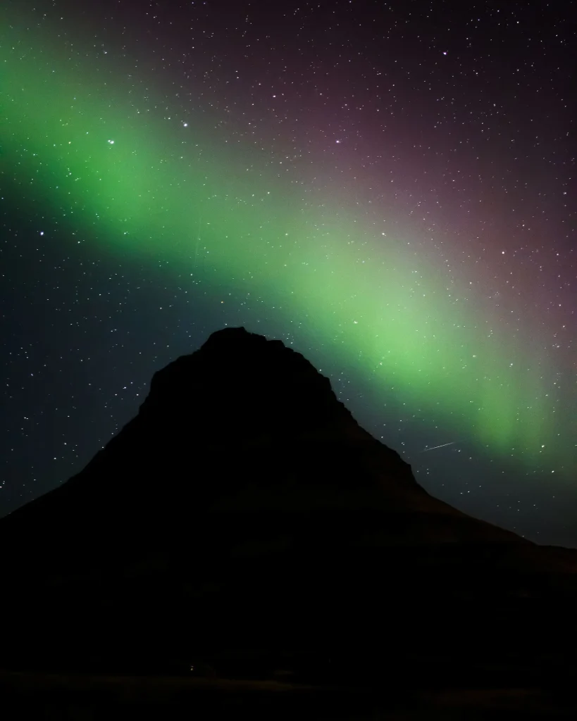 The green aurora borealis swirling over a snowy Icelandic landscape, illustrating an Iceland northern lights trip for women over 50.