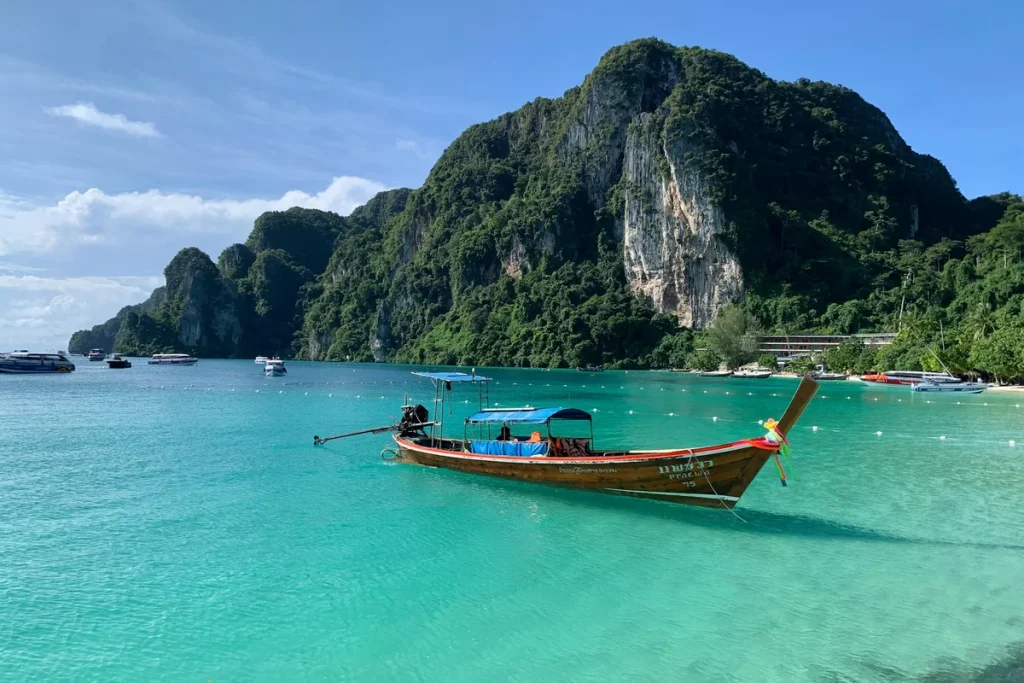 Longtail boats on a turquoise bay among limestone cliffs in Thailand, illustrating safe and elegant Thailand solo travel for women over 50.