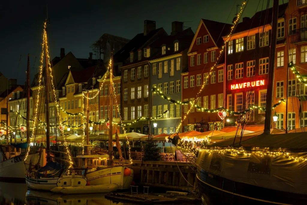 Copenhagen Christmas market at Nyhavn, wooden stalls and fairy lights along the colorful painted harbor houses at dusk