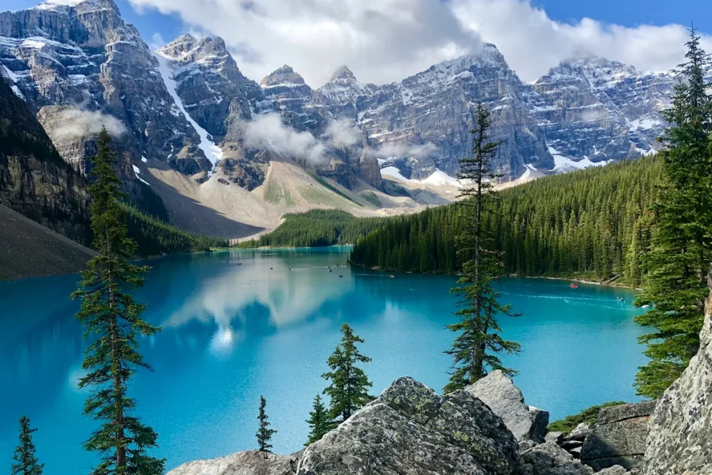 Solo travel Canada: the turquoise water of Moraine Lake below the snow-capped Valley of the Ten Peaks and pine forest in Banff National Park, Alberta