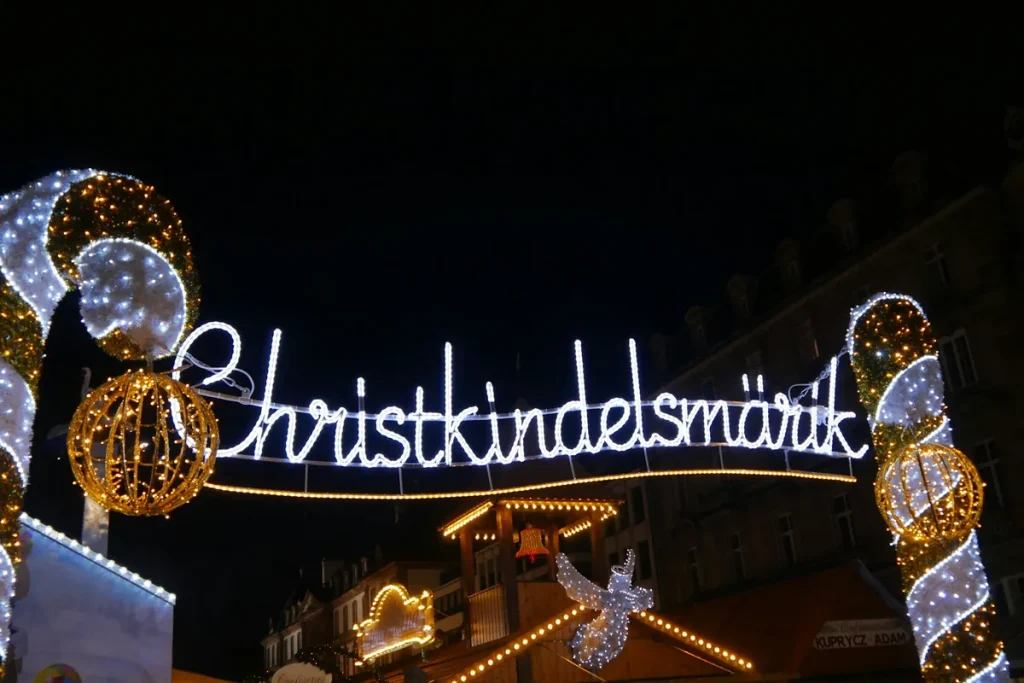 The illuminated Christkindelsmärik sign glowing over Strasbourg Christmas market at night