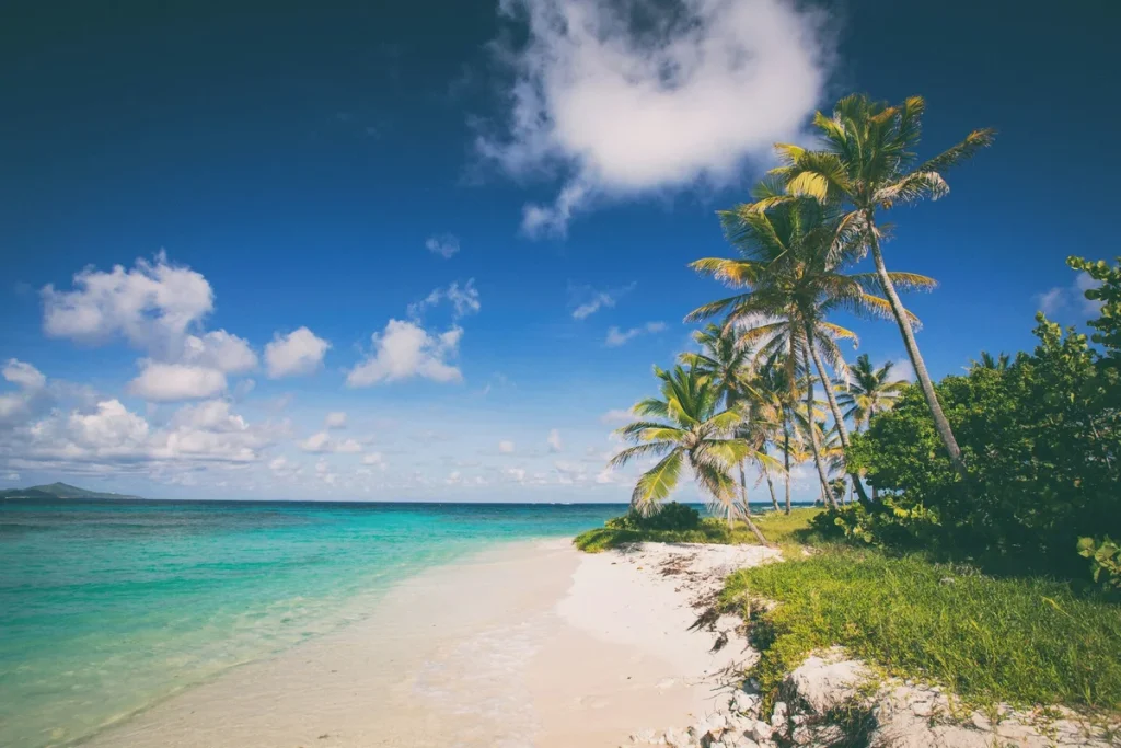 best Caribbean islands to visit for solo women over 50, a calm turquoise bay and pale-sand beach under a bright sky