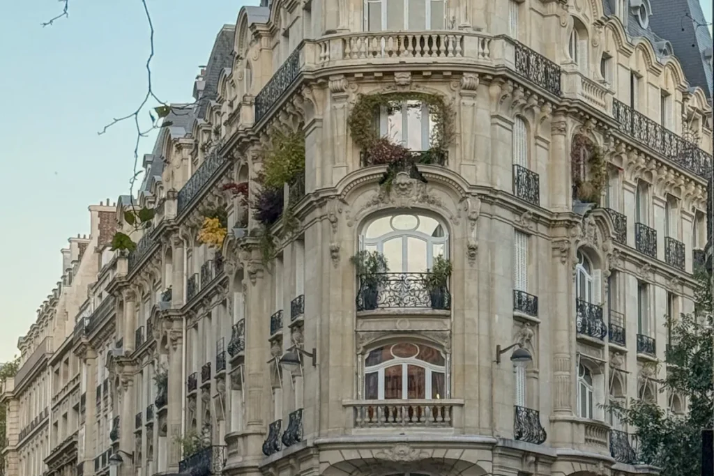 A grand Haussmann corner building with wrought-iron balconies on an elegant Paris street, where to stay in Paris for women over 50